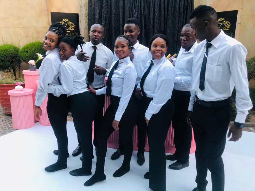 Group of waitstaff in uniform posing for a photo.