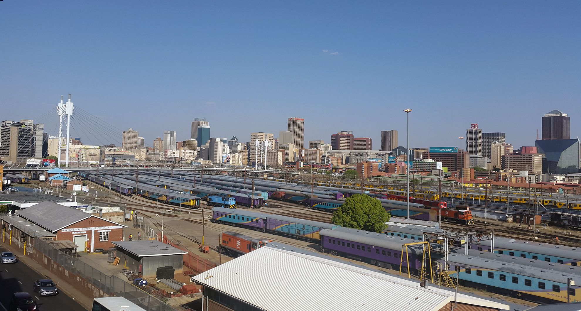 Panoramic view of Johannesburg skyline with buildings and trains.