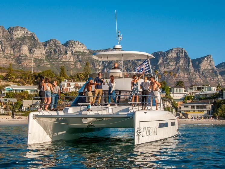 Luxury catamaran with guests on board near Cape Town coastline