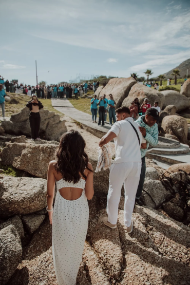 Couple walking towards an outdoor wedding setup with guests in the background.