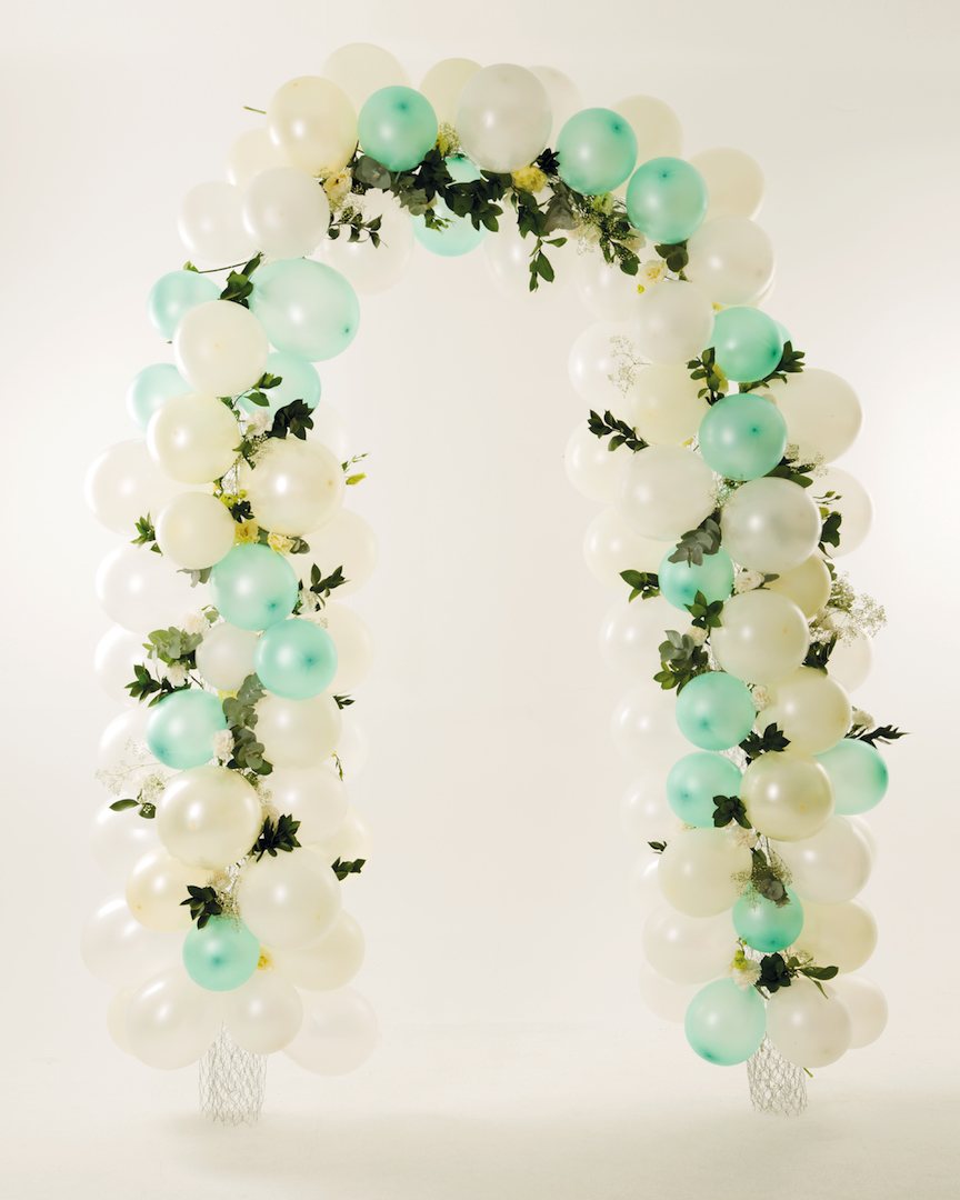 A colourful balloon arch with mint and white balloons and greenery