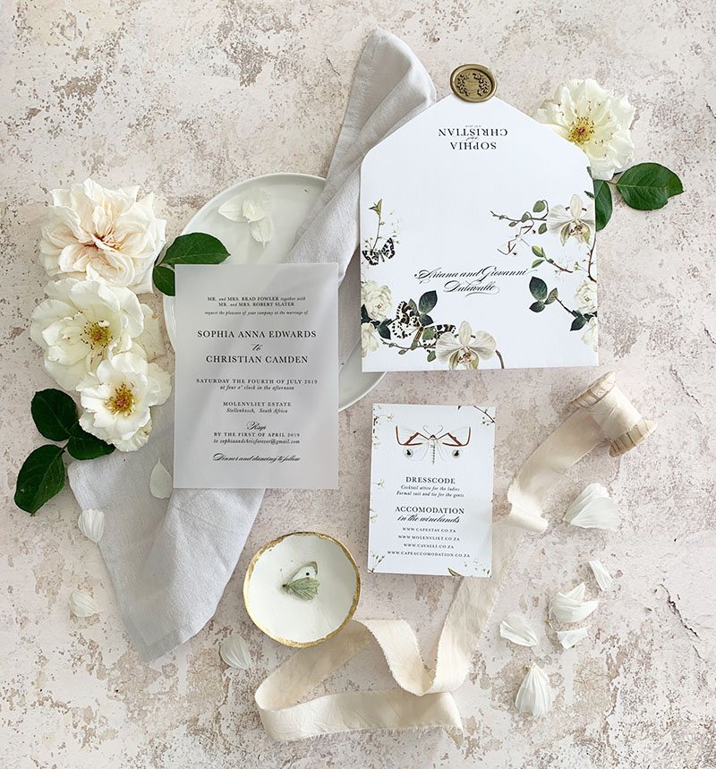 Flat lay of a wedding invitation suite with floral accents.