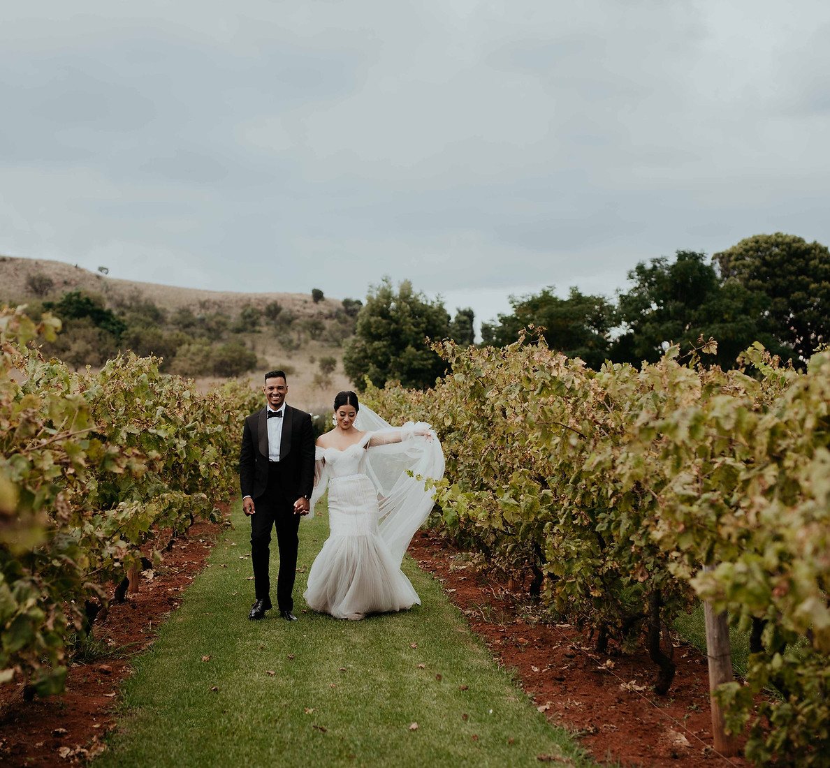 Couple walking hand in hand through a vineyard