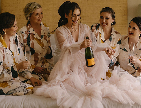 Bridal party in matching pajamas celebrating with champagne