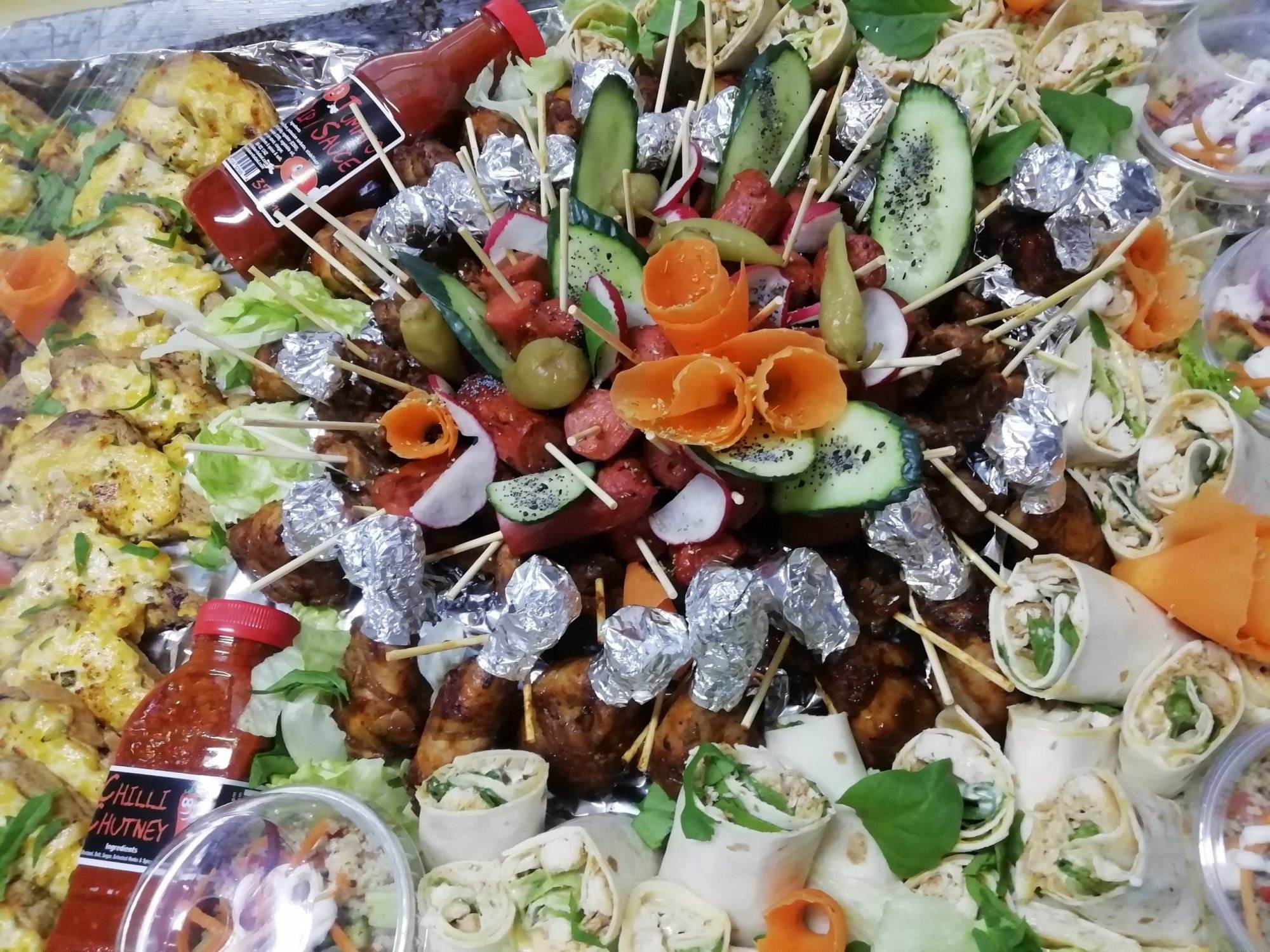 Colorful platter of halaal food including rolls, skewers, and sauces
