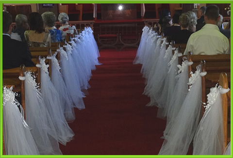 White tulle aisle runners with floral decorations in a church