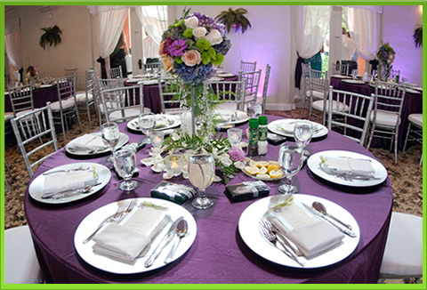 Round table beautifully set with purple runners and floral centerpiece.