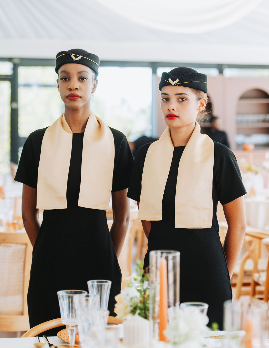 Two professional event hosts in black uniforms with cream scarves