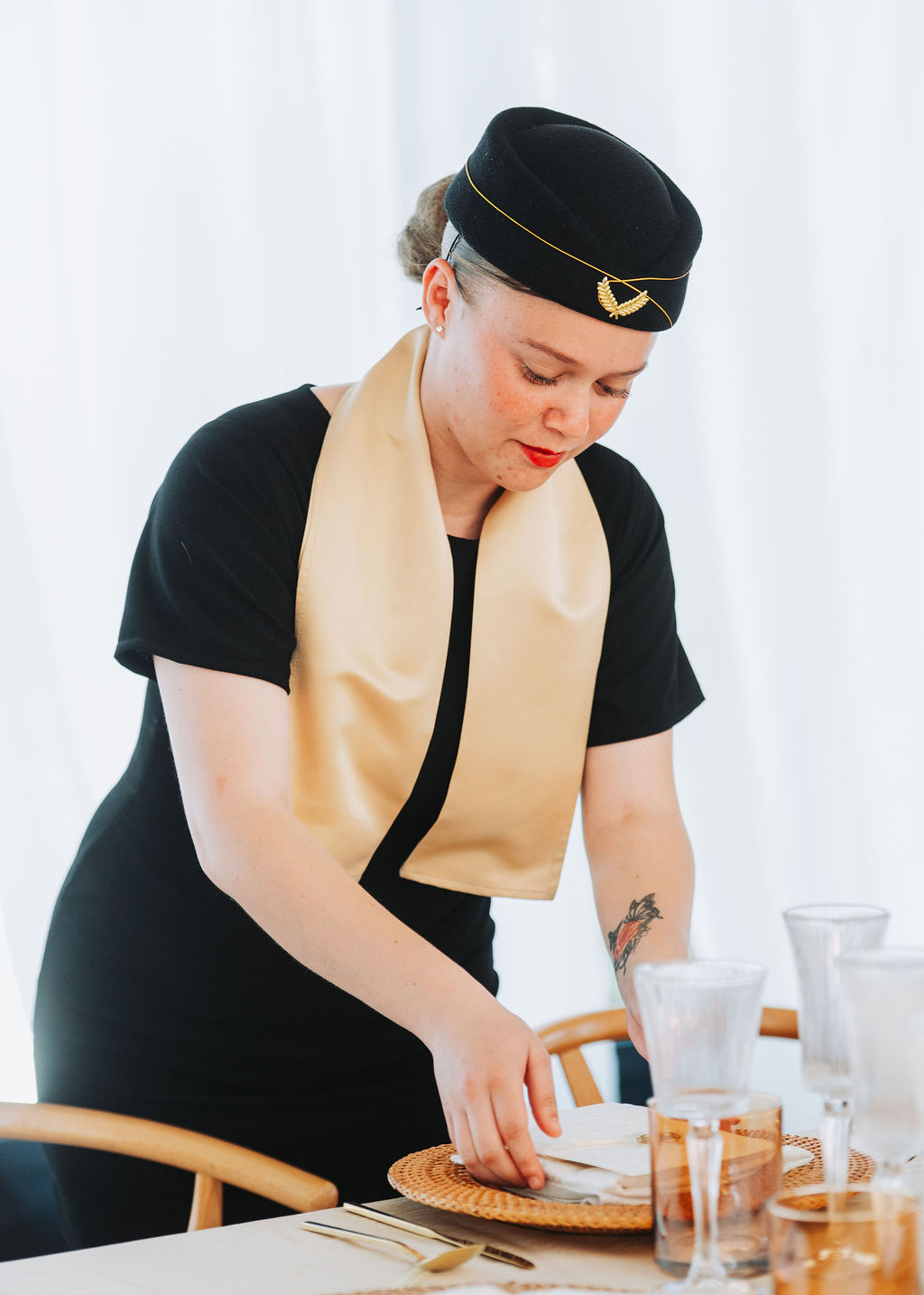 A hostess setting a table with elegant decor.