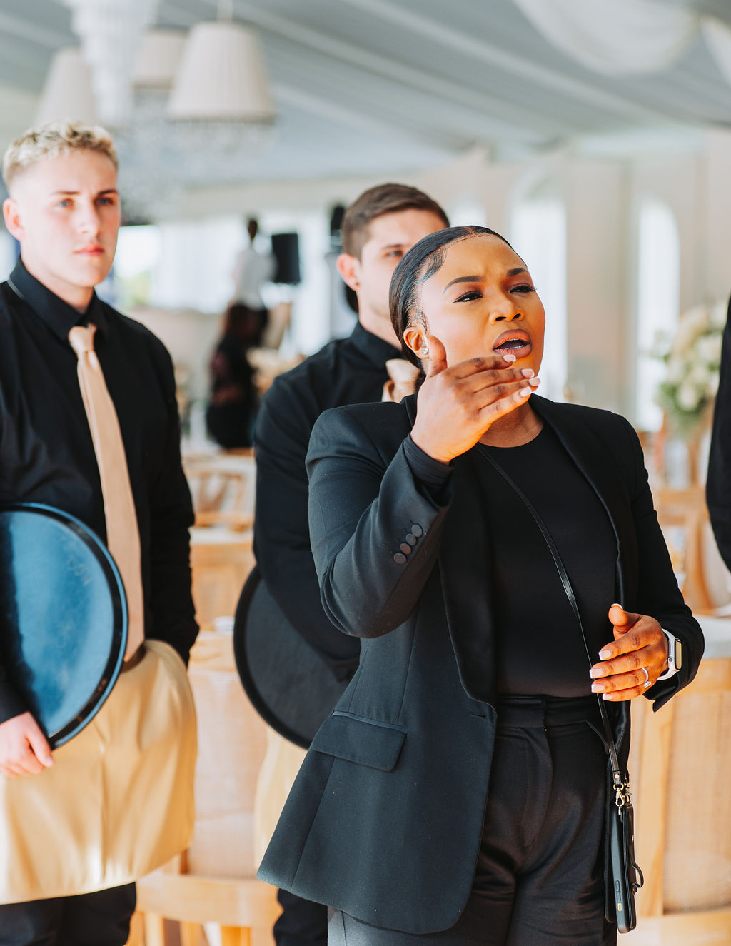 A woman and male staff members in formal attire engaged in event preparations.