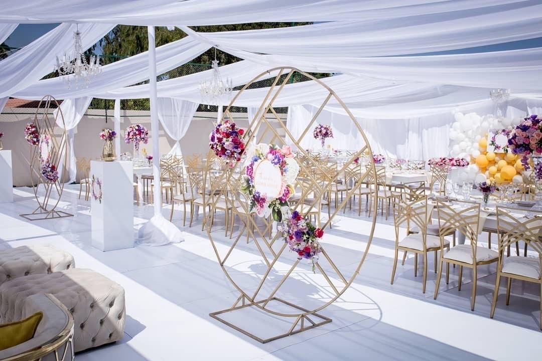 Outdoor event setup with white flooring and floral decorations.