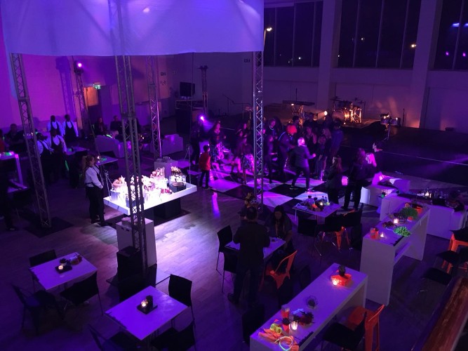 Event space with tables and guests under purple ambient lighting