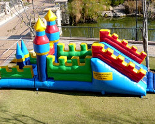 Vibrant castle-themed water slide on green grass.