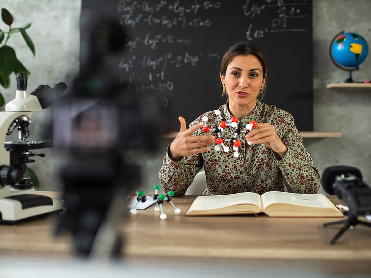 A presenter explaining with molecular models during a live streaming setup.