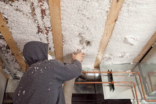 A worker installing insulation in a ceiling
