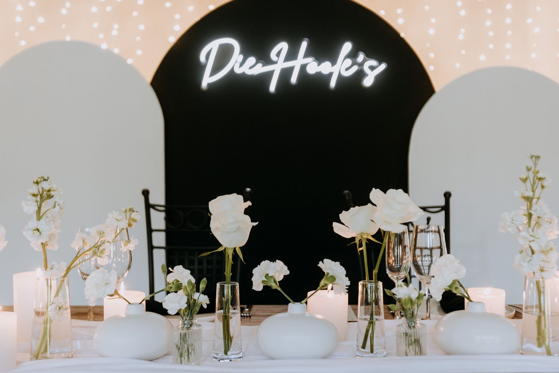 Minimalist floral table setup with white flowers and candles.