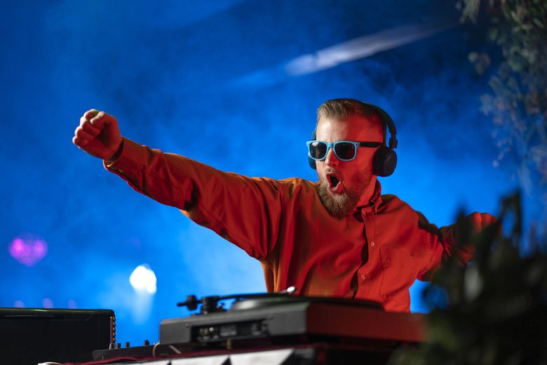 DJ with headphones and sunglasses performing at an event
