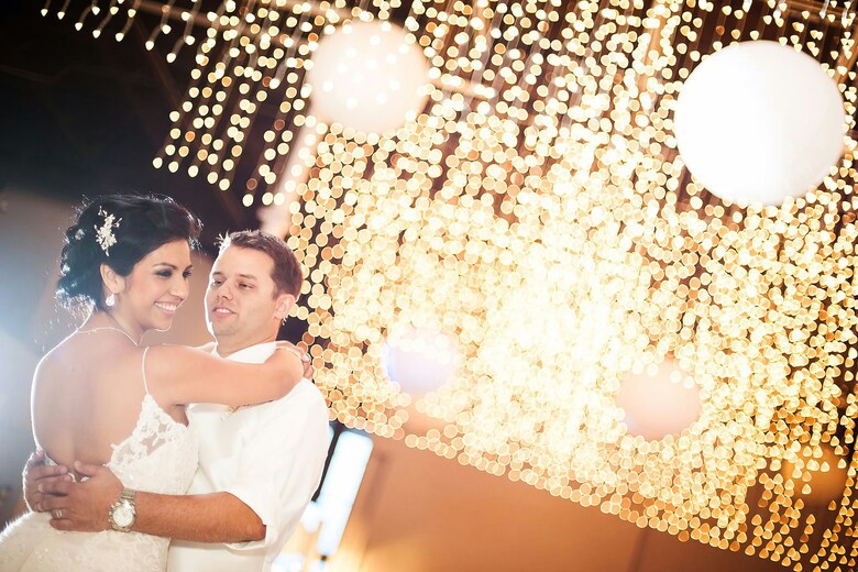 Couple dancing under fairy lights at their wedding.