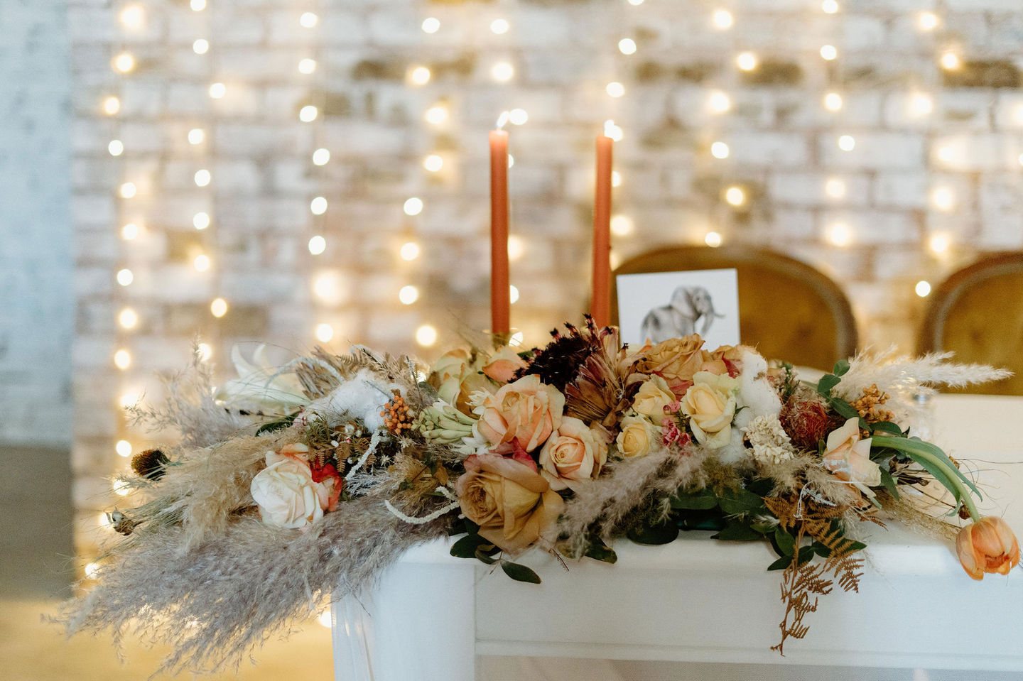 Floral table arrangement with candles on a white table