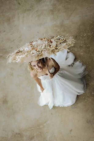 Bride holding a floral parasol dressed in a wedding gown.